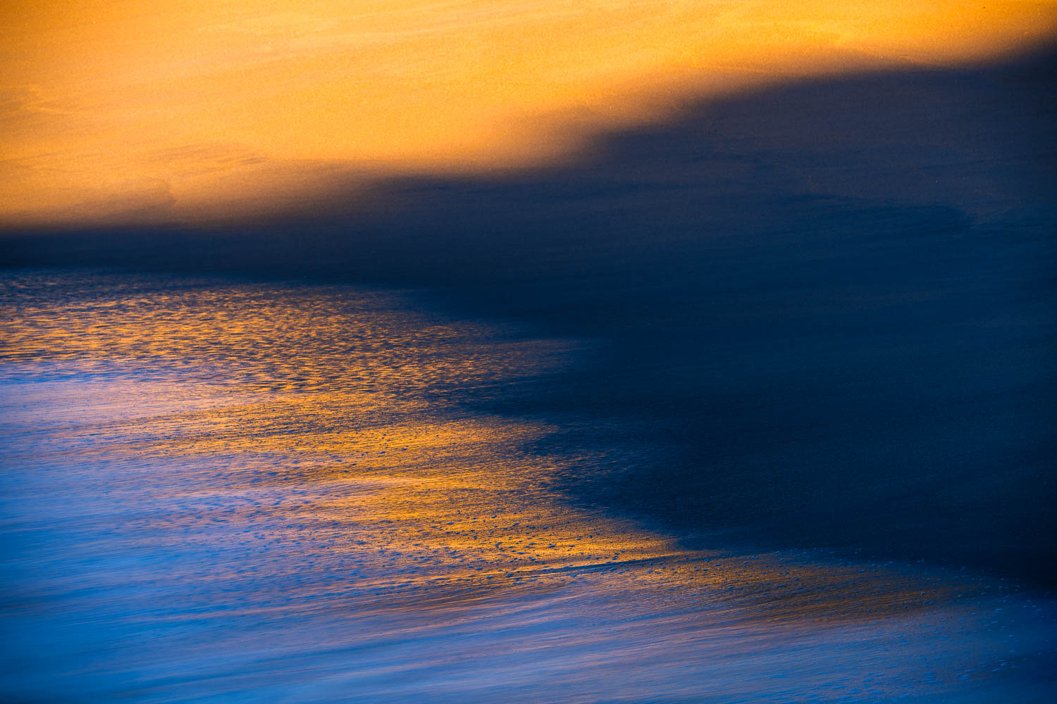 Convergence Golden beach, dark shadow, and incoming waves converge into three triangular shapes